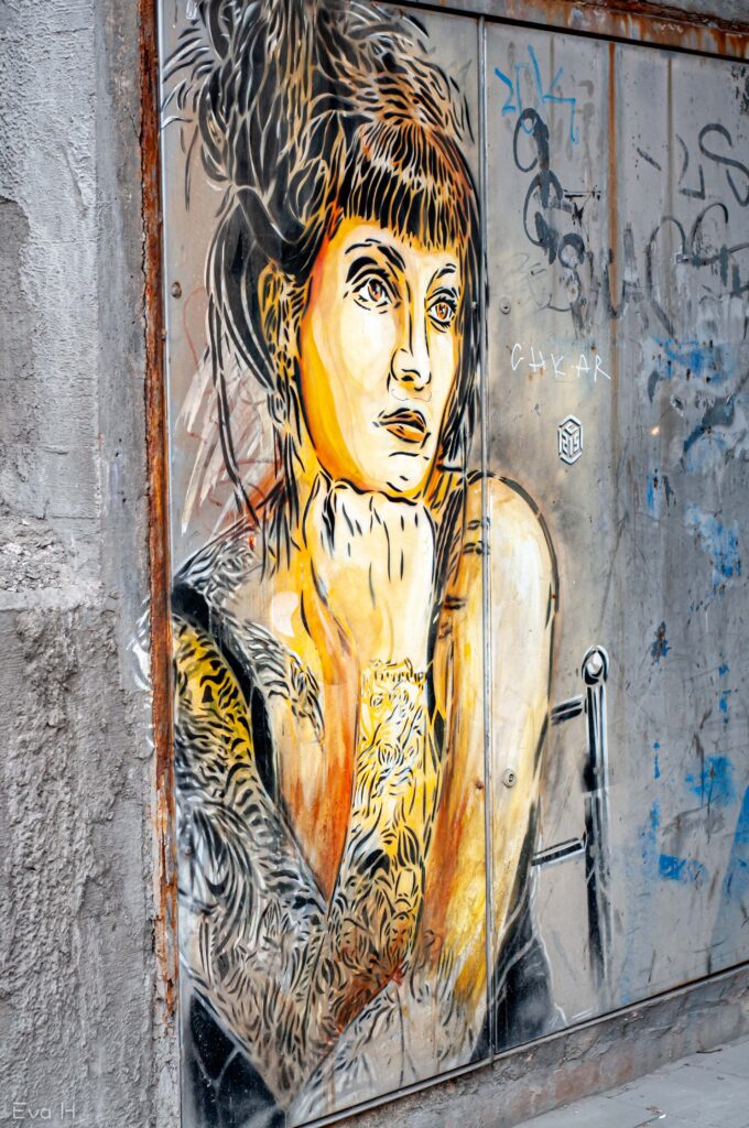 Tatovert kvinne, gult og sort. Tiger-liknende. Malt på betong. Gatekunst. Fotografi