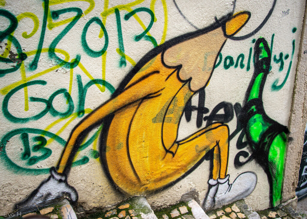 Gul blyant sitter i trappa. Diverse grafitti på veggen rundt. Gatekunst fra Lisboa. Fotografi