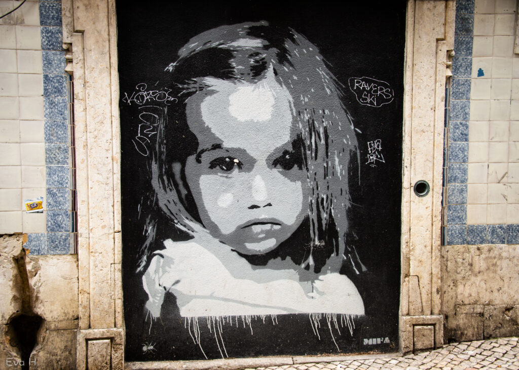 Sort/hvitt maleri i gjenmurt portåpning. Lita jente ser skeptisk på verden. Gatekunst. Lisboa. Fotografi