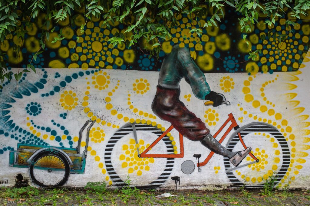 Syklist malt på mur går i ett med bakgrunnen. Gatekunst Bergen. Fotografi