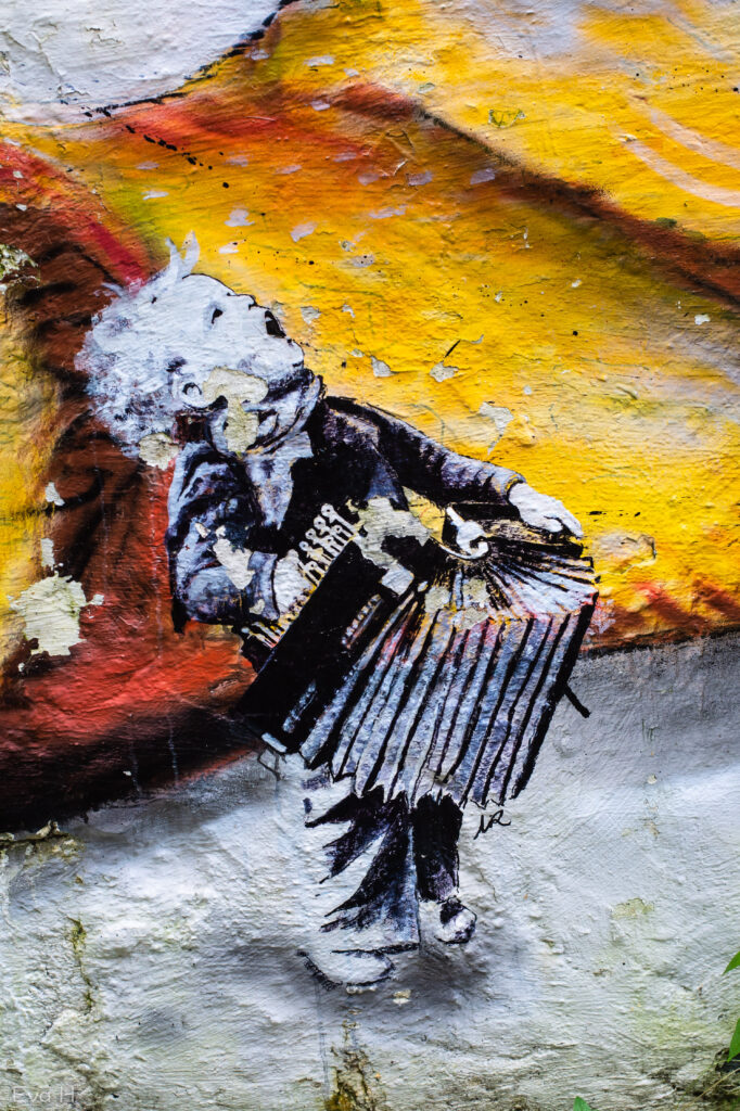 Liten gutt spiller trekkspill. Malt på mur. Detalj av gatekunst fra Bergen. Fotografi