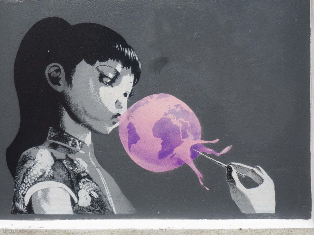 Jente stikker hull på jordklode-ballong. Gatekunst fra Bergen. Fotografi
