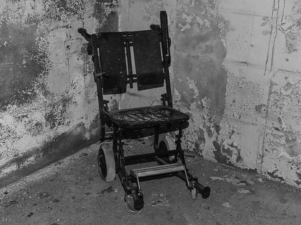 Slitt gammel rullstol i kjellerrom med slitt murvegg